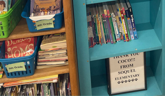 Path to Literacy Bookshelves at Soquel Elementary filled with childrenโs books, with a small sign reading โThank You Coco!!! From Soquel Elementary.โ