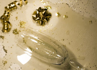 Toasting Moderation Broken champagne flute surrounded by gold ribbon and glitter on a white surface, symbolizing the aftermath of holiday overindulgence.