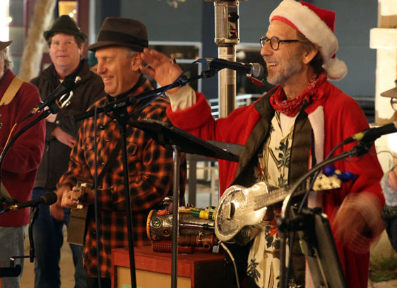 Things to do in Santa Cruz A holiday jug band performs live onstage, with musicians singing into microphones and playing acoustic instruments.