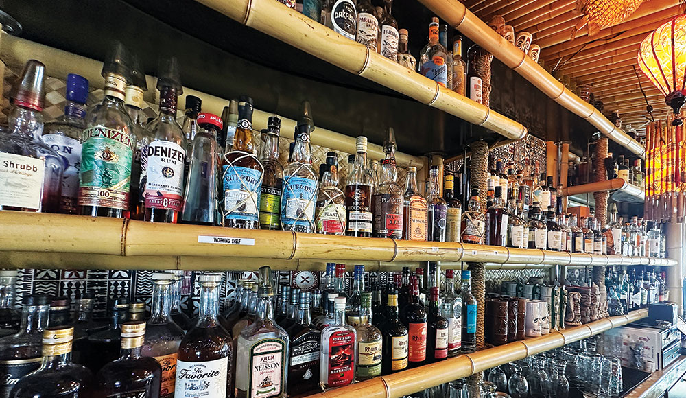 Rows of liquor in a bar with rattan shelves