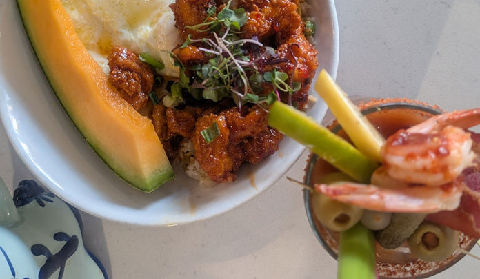 Franchise Player Korean chicken fried rice with fried egg and melon, alongside a loaded Baltimore Bloody Mary with prawns and bacon at The Breakfast Club.