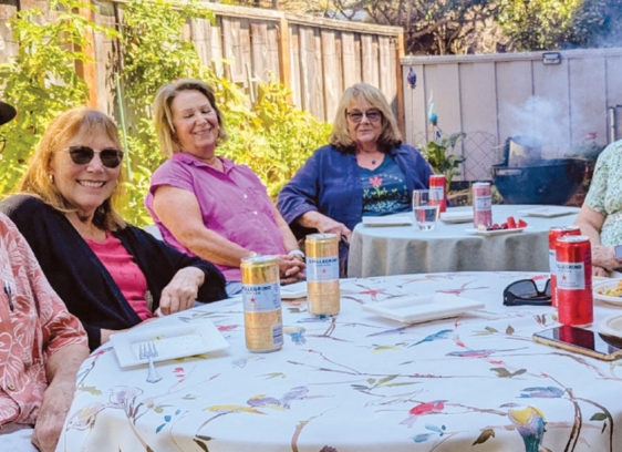Be Prepared Members of Village Santa Cruz County gather around a table outdoors, enjoying conversation and refreshments together.