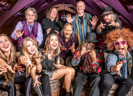 Things to do in Santa Cruz Members of Moonalice pose together inside a wood-paneled performance space, reaching toward the camera.