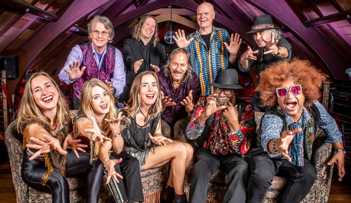 Things to do in Santa Cruz Members of Moonalice pose together inside a wood-paneled performance space, reaching toward the camera.