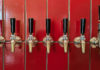 Level-Up Liquids A row of polished beer taps mounted against a glossy red tile wall inside Other Brother Beer Co.