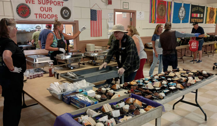 The Wednesday Lifeline Volunteers prepare and serve meals inside the Santa Cruz Veterans Memorial Building during the weekly Veterans Meal and Pantry Program.