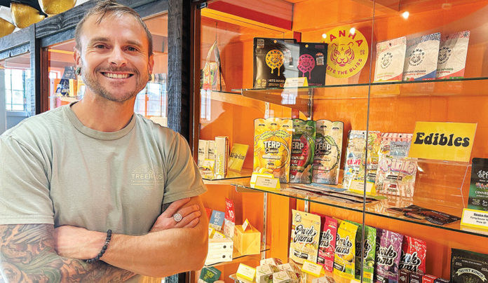 Santa Cruz County Moves Closer to Cannabis Consumption Lounges Man standing in front of a display of cannabis products