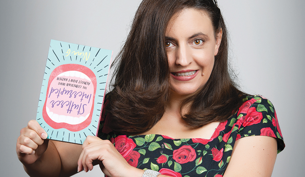 Comedian Nina G holds a copy of her memoir while posing for a portrait.