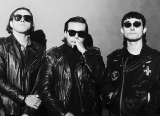 Things to do in Santa Cruz Three musicians wearing black leather jackets and sunglasses pose for a black-and-white portrait.