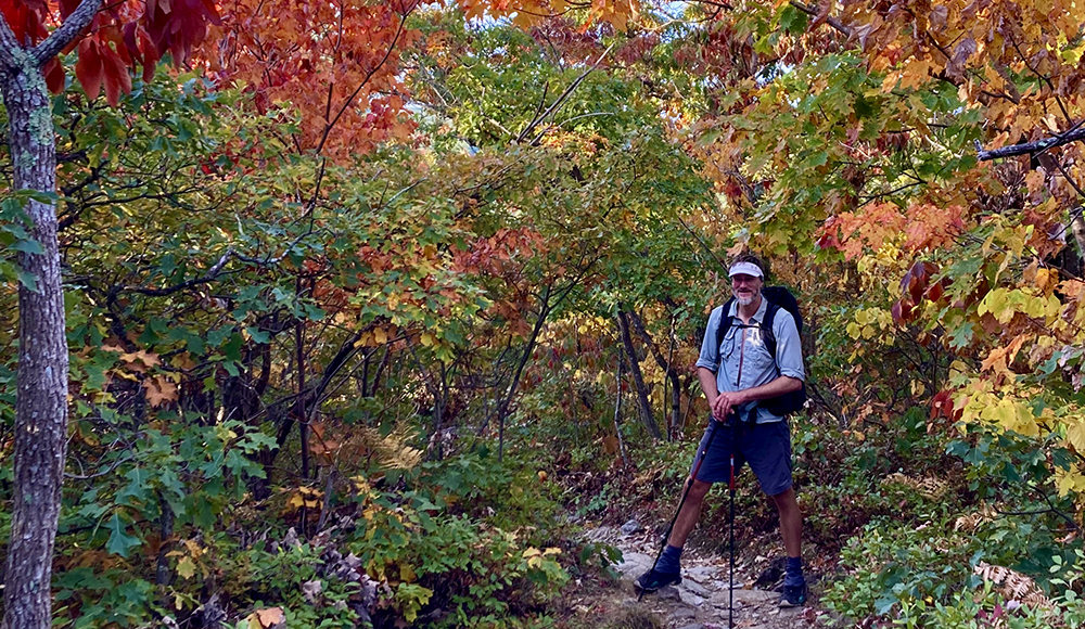 Jared Perry hiking through autumn foliage on the Appalachian Trail in New Hampshire.
