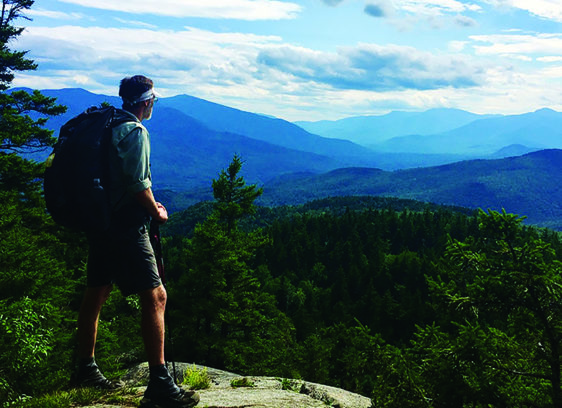 The Editor’s Desk Hiker looks out over forested mountains during a long-distance trek