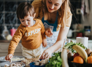 An adult and young child prepare food together in a home kitchen.