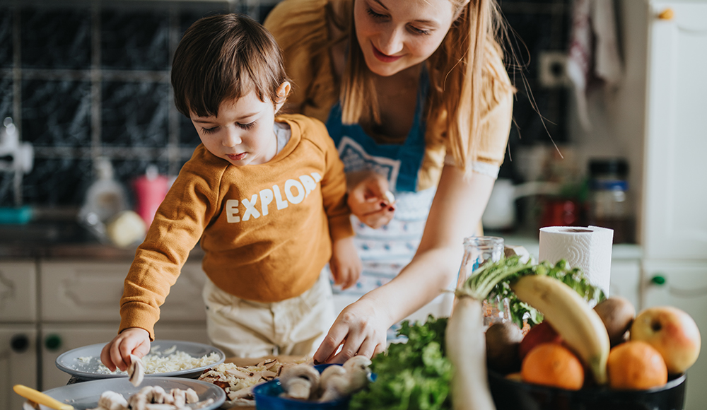 An adult and young child prepare food together in a home kitchen.
