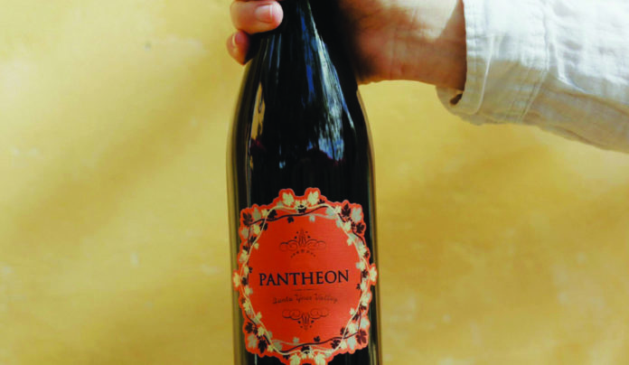 Cranberry & Clove A bottle of Demetria Estateโs 2023 Pantheon red wine held against a warm background