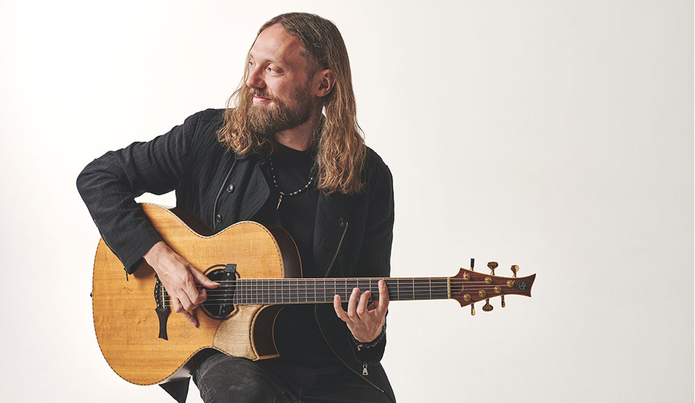 Guitarist Mike Dawes holding an acoustic guitar