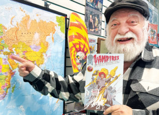 50 Years of Atlantis Fantasyworld Joe Ferrara holding a Vampires Everywhere comic beside a world map inside Atlantis Fantasyworld