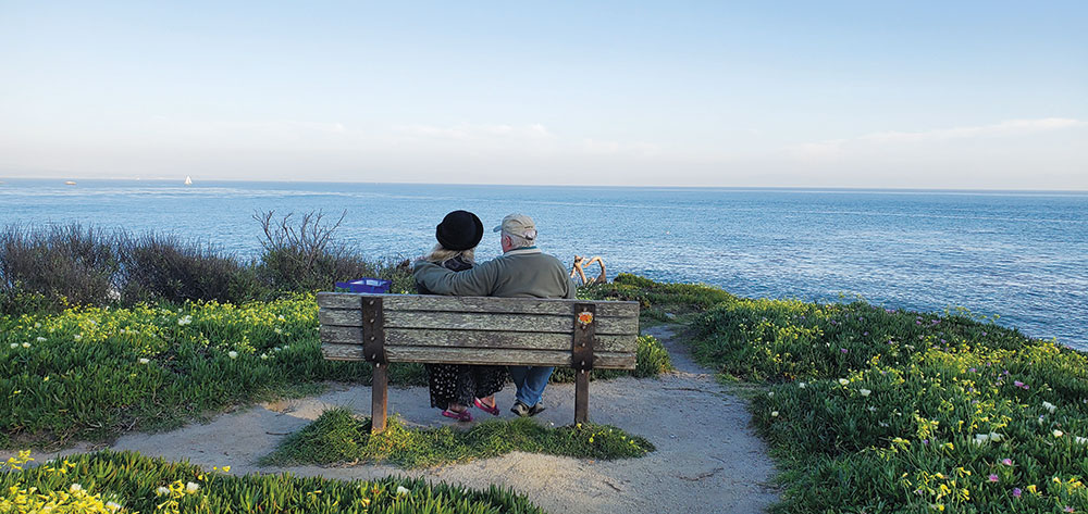 Couple sitting on a bench overlooking Monterey Bay on West Cliff in Santa Cruz