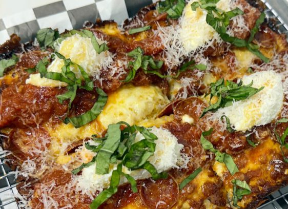 Cheesy Check d20’s entry into the pizza game features Detroit-style pies with a thick, airy crust and crisped Wisconsin brick cheese.