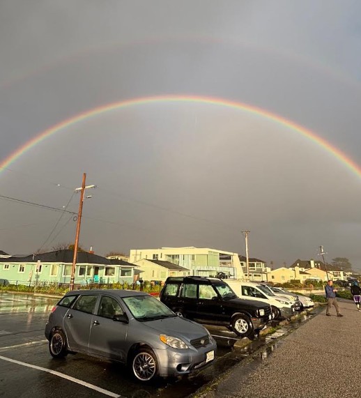 Double rainbow arches over parked cars and homes along West Cliff Drive in Santa Cruz after a winter storm.
