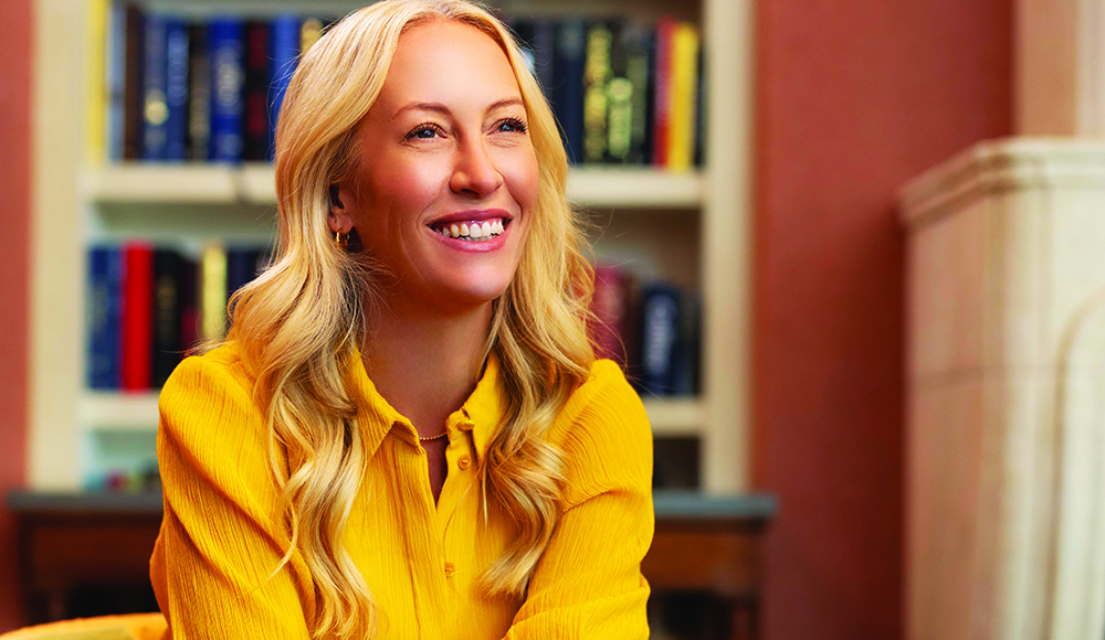 Julia Hartz smiles during an interview, seated indoors with bookshelves behind her