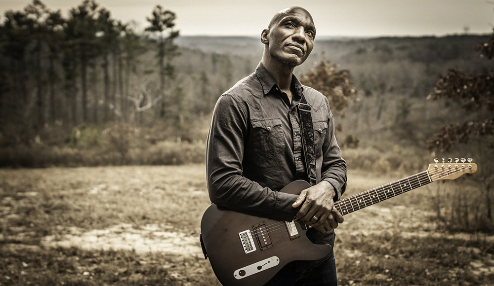 Blues musician Cedric Burnside holding electric guitar outdoors