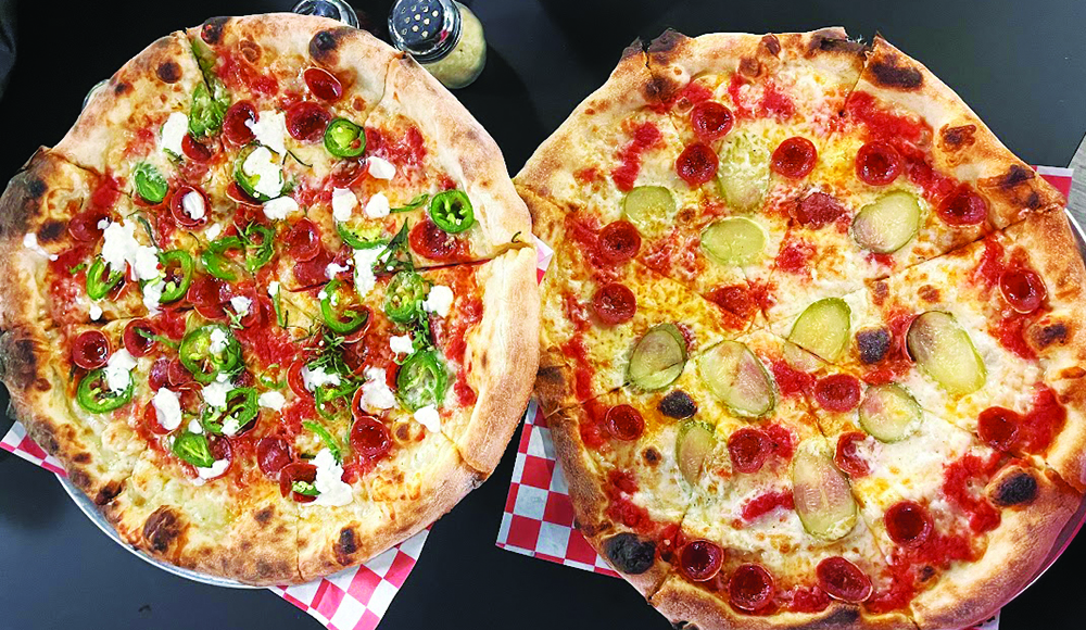 Two wood-fired pizzas at Pogonip Pizza topped with pepperoni, dill pickles, jalapeño, mozzarella and hot honey.