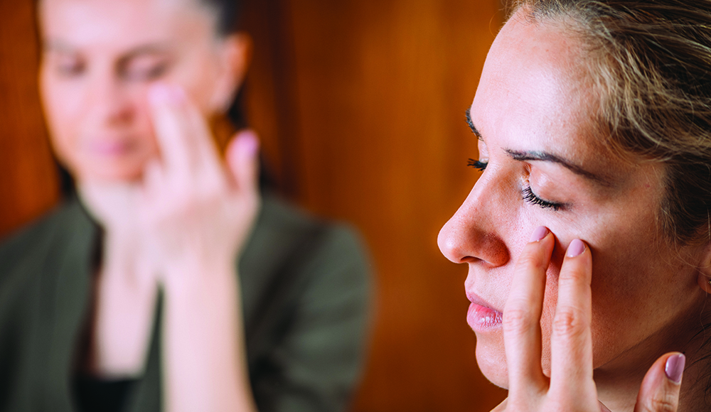 Woman gently tapping her face in a stress relief technique known as Emotional Freedom Technique.