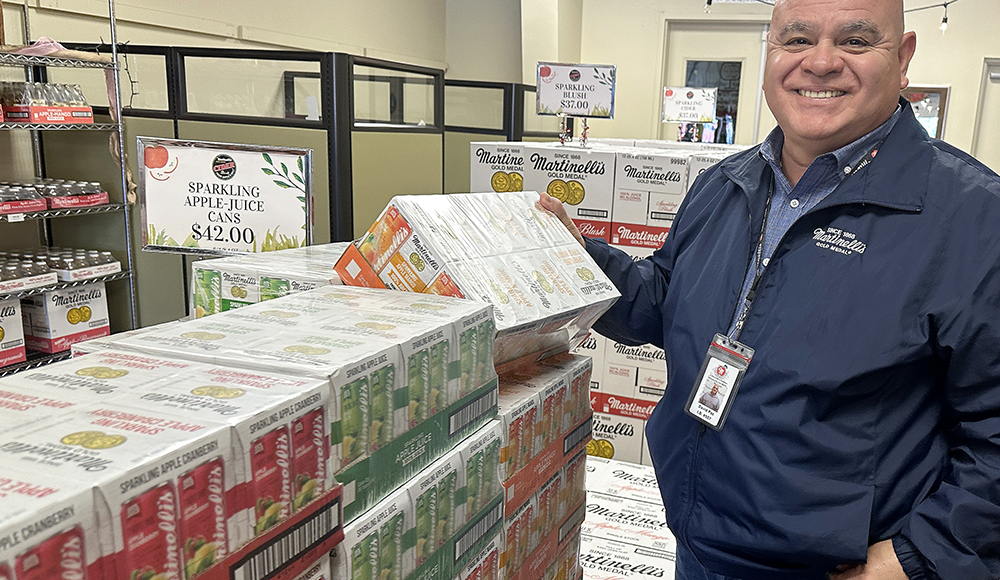 Man stands beside stacked cases of Martinelli’s sparkling beverages at Watsonville Municipal Airport