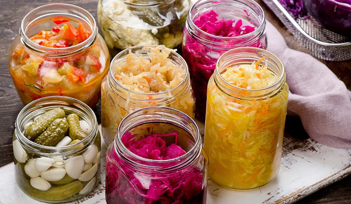 Good Gut Jars of fermented vegetables including sauerkraut, pickles, and colorful cabbage on a rustic table