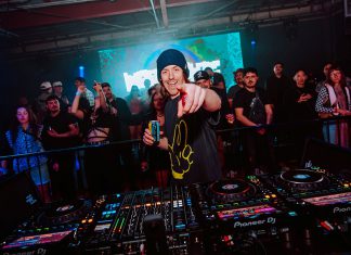 DJ Neumonic Beats Big DJ performing live at a crowded Santa Cruz nightclub, pointing toward the camera behind a Pioneer DJ mixing console
