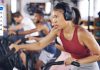 Don’t Block Health Woman exercising on cardio machine at fitness class wearing headphones