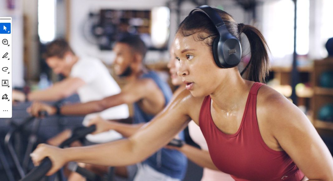Woman exercising on cardio machine at fitness class wearing headphones