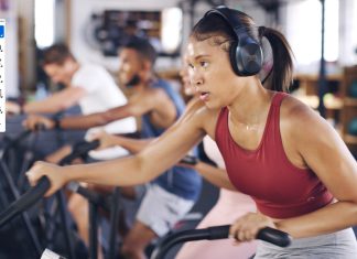 Don’t Block Health Woman exercising on cardio machine at fitness class wearing headphones