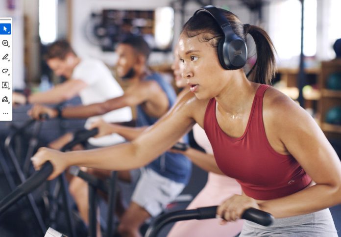 Donโt Block Health Woman exercising on cardio machine at fitness class wearing headphones