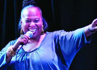 The Voice Tammi Brown singing on stage holding microphone and smiling during live performance