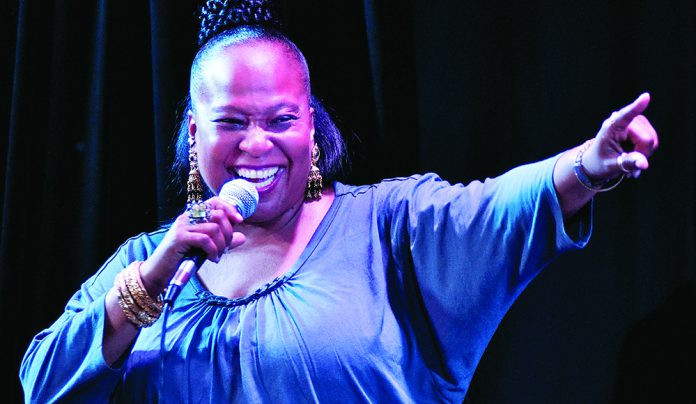The Voice Tammi Brown singing on stage holding microphone and smiling during live performance