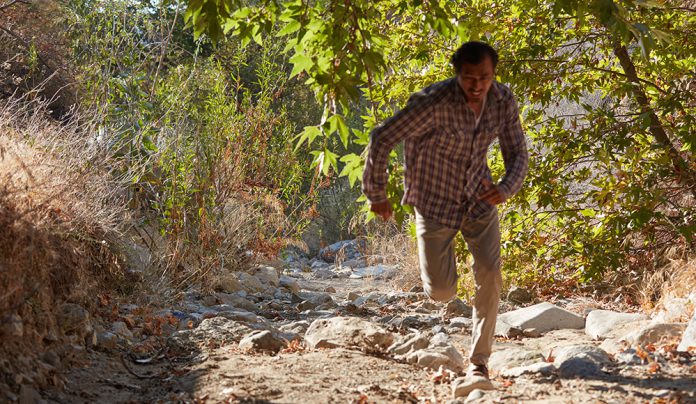 The Editor’s Desk Actor Geovanni Ryan running through a wooded path in Hangtown