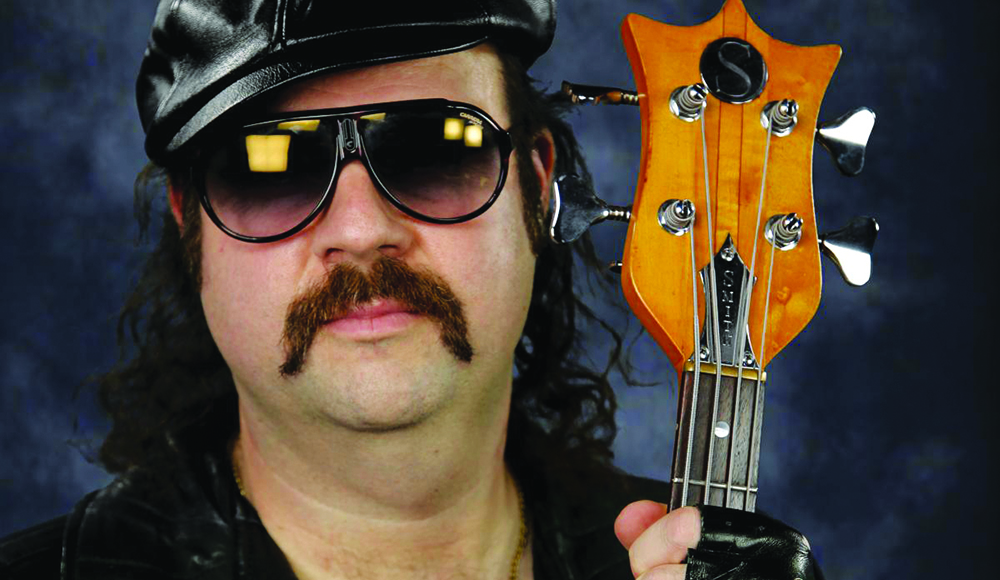 Donny Benét wearing sunglasses and holding a bass guitar