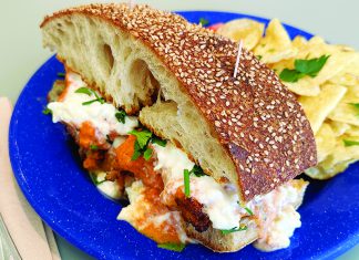 Brew Chew Chicken parmesan sandwich with melted cheese and chips on blue plate