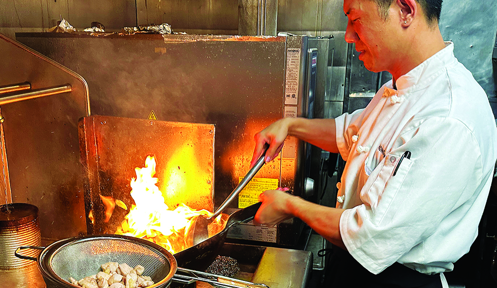 Chef Hongmin Mo cooking with flames in Fusion Fare kitchen
