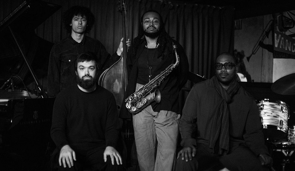 Immanuel Wilkins Quartet posing with saxophone and upright bass in a black and white portrait
