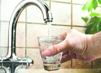 Is Our Water Safe? Hand holding a glass of water being filled from a kitchen faucet