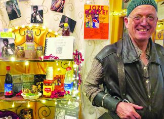 Spicy Trip Chef Jozseph Schultz smiling inside a colorful shop surrounded by spices and cookbooks