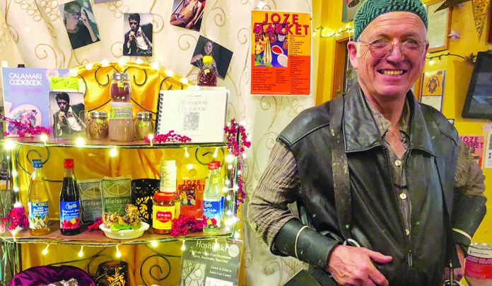 Spicy Trip Chef Jozseph Schultz smiling inside a colorful shop surrounded by spices and cookbooks