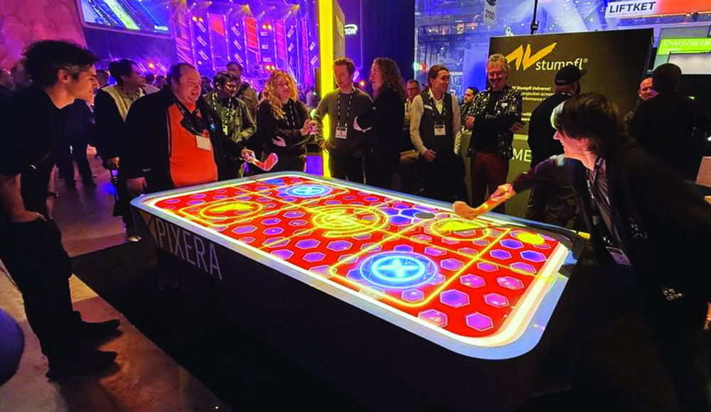 People playing interactive digital air hockey table with projected puck