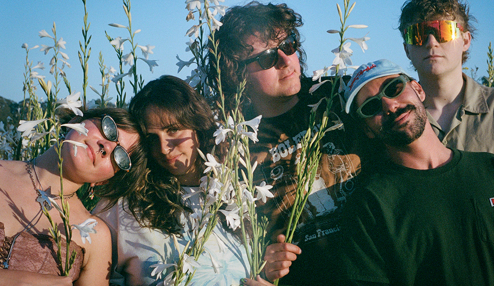 Members of Mild Universe band posing with flowers outdoors