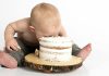 Baby Food Baby smashing face into small frosted cake on wooden stand