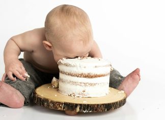 Baby Food Baby smashing face into small frosted cake on wooden stand