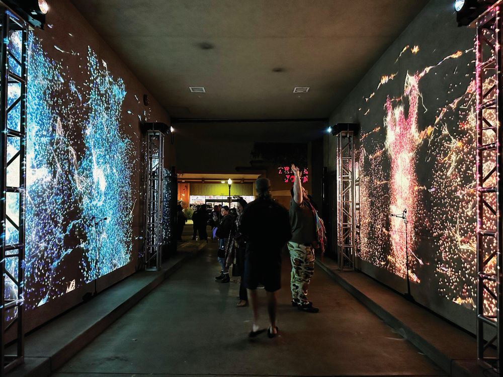 People walking through immersive LED installation with colorful projections on walls