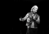 Send in the Lagoonies Black-and-white photo of a stand-up comedian in a leather vest holding a microphone on stage at Blue Lagoon in Santa Cruz